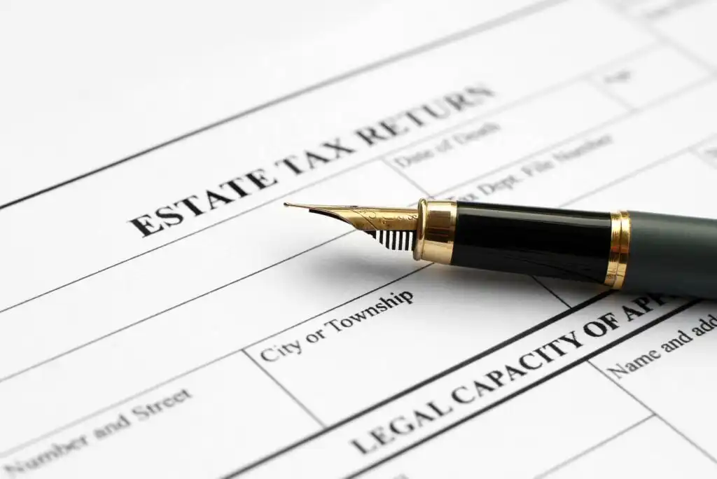 A close-up of a fountain pen resting on an estate tax return form, showing spaces for entering information such as name, city, or township.