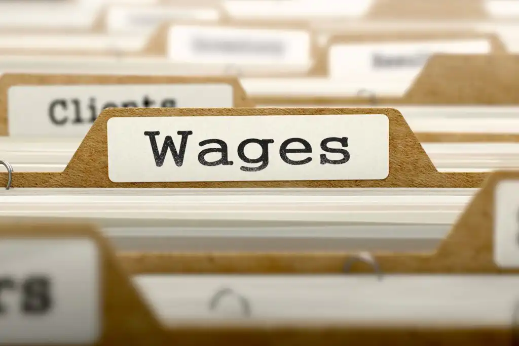 A close-up of a file folder tab labeled Wages among other labeled folders in a filing system, suggesting organization of financial or employment documents.