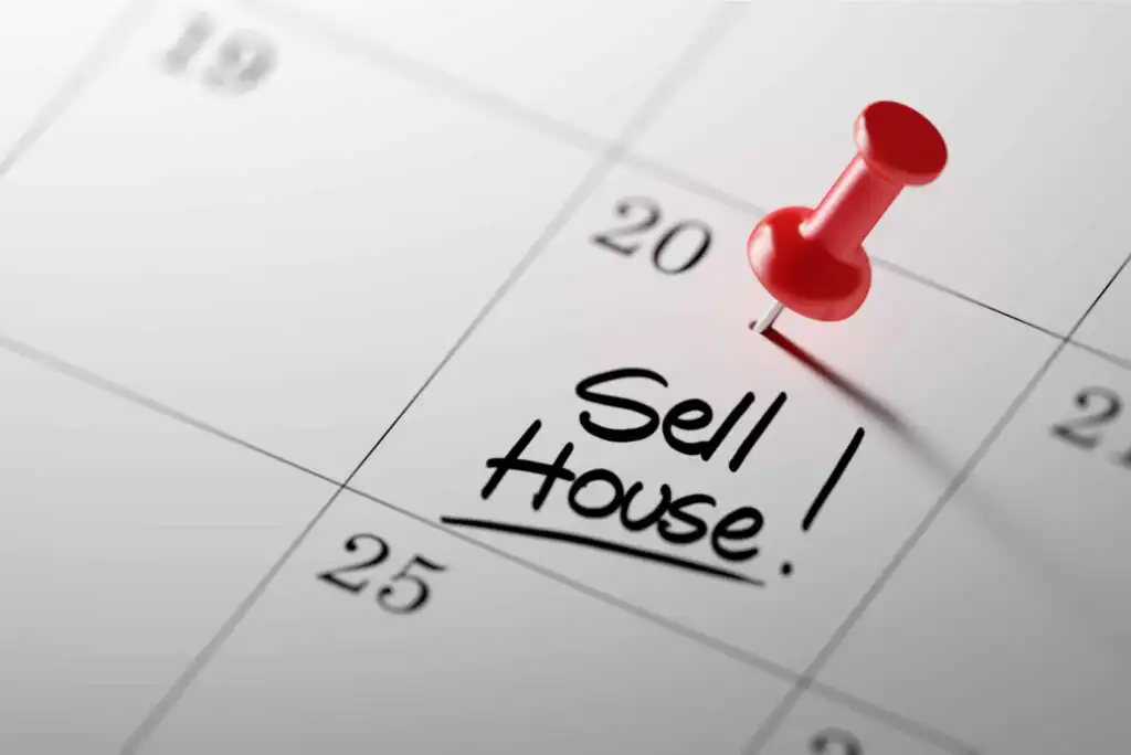 A close-up of a calendar with a red pushpin marking the 20th day. The words Sell House! are handwritten and underlined on that date. The calendar background is white with gray numbers.