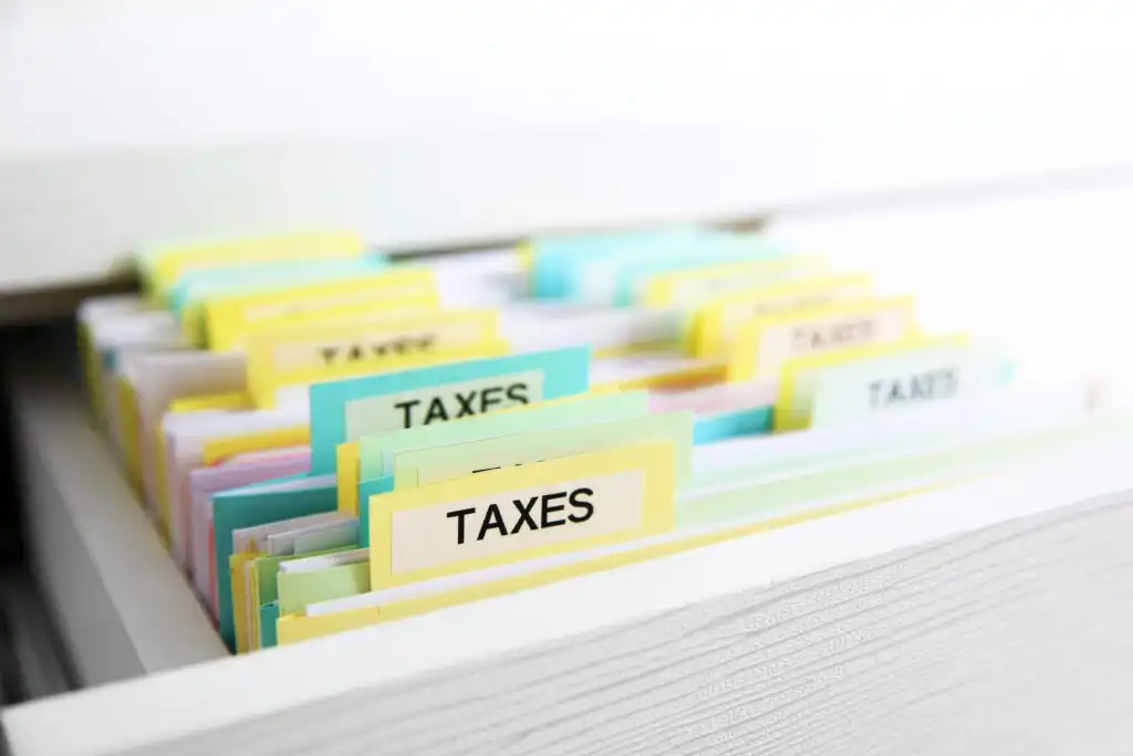 A drawer filled with colorful labeled folders, with several folders marked TAXES in bold letters, organized for easy access and filing.