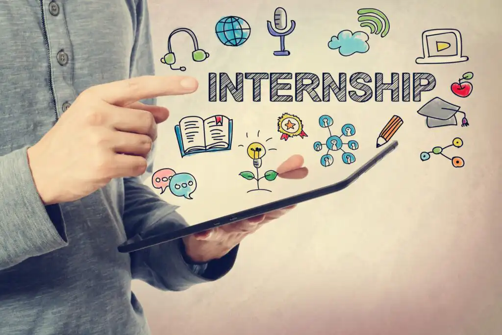 A person holds a tablet with colorful internship-related icons floating above it, including books, a globe, chat bubbles, a headset, a diploma, and the word INTERNSHIP in bold letters.